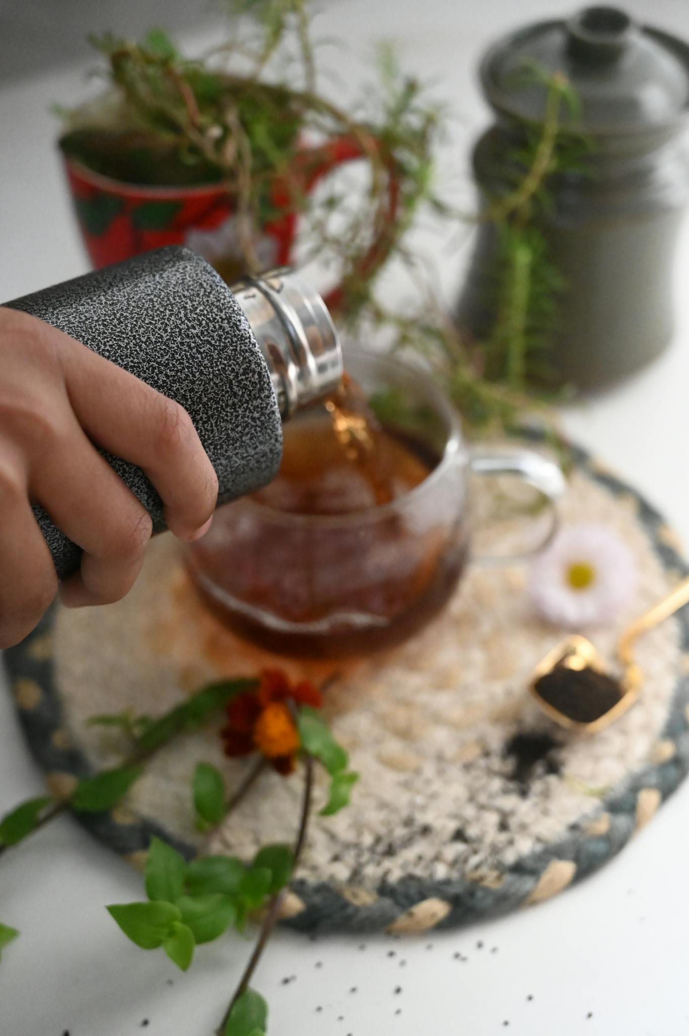 A hand pours black tea into a glass cup on a decorated table in Chattogram, Bangladesh.